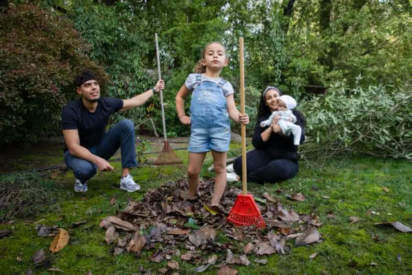 Image of young girl with family raking leaves