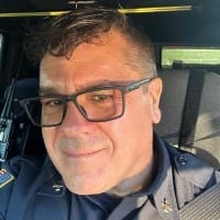 Headshot of a middle aged man wearing glasses and smiling.