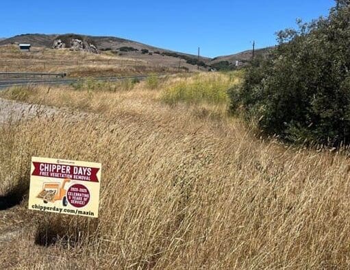 chipper day sign in a field of dry grass with hills in the background.