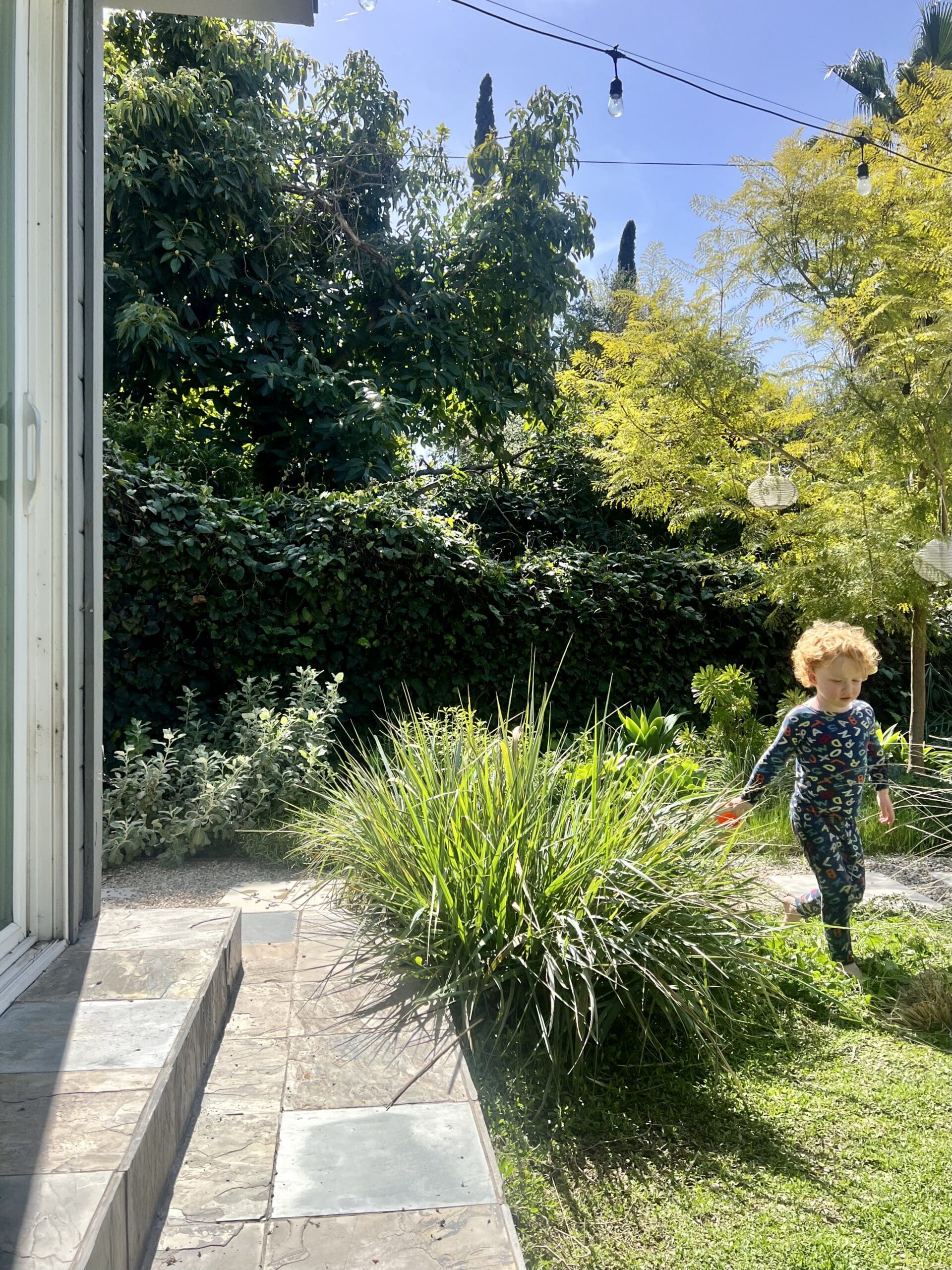 A young child with fluffy blond hair is running trough a garden.