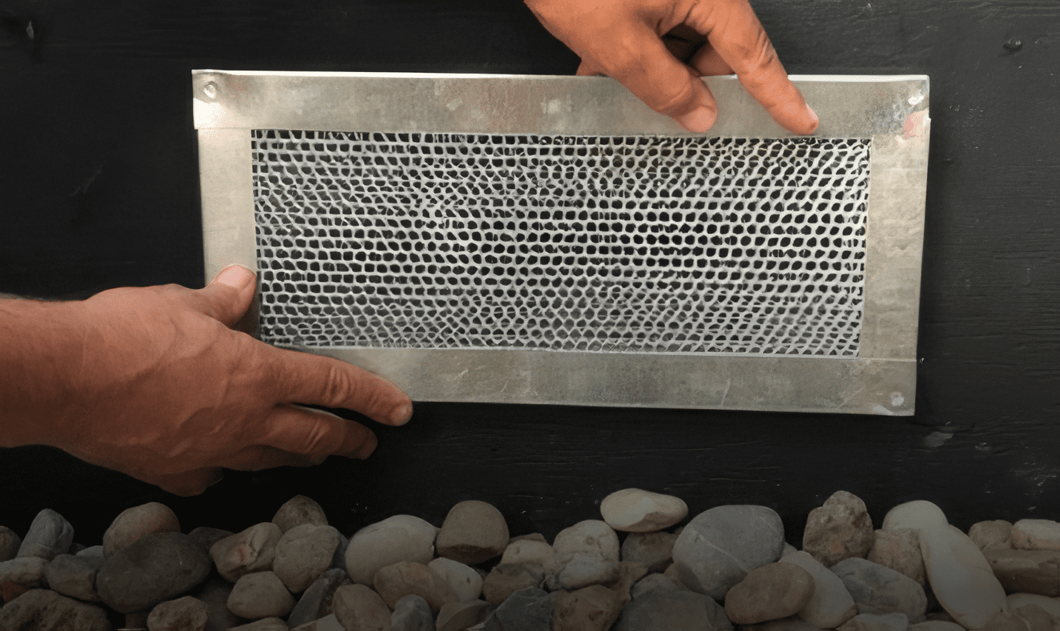 man displaying metal vent outside of house