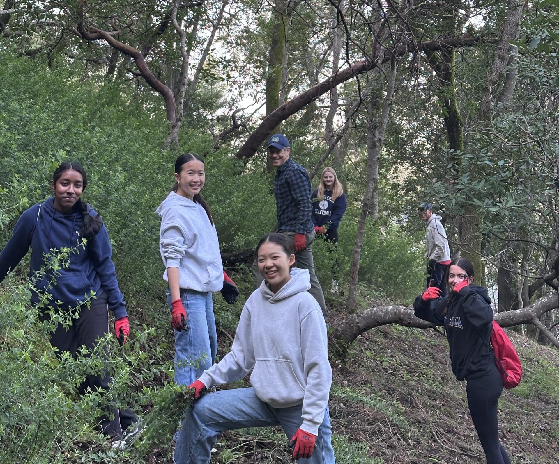 Group of high school aged students in the woods, all smiling at the camera.