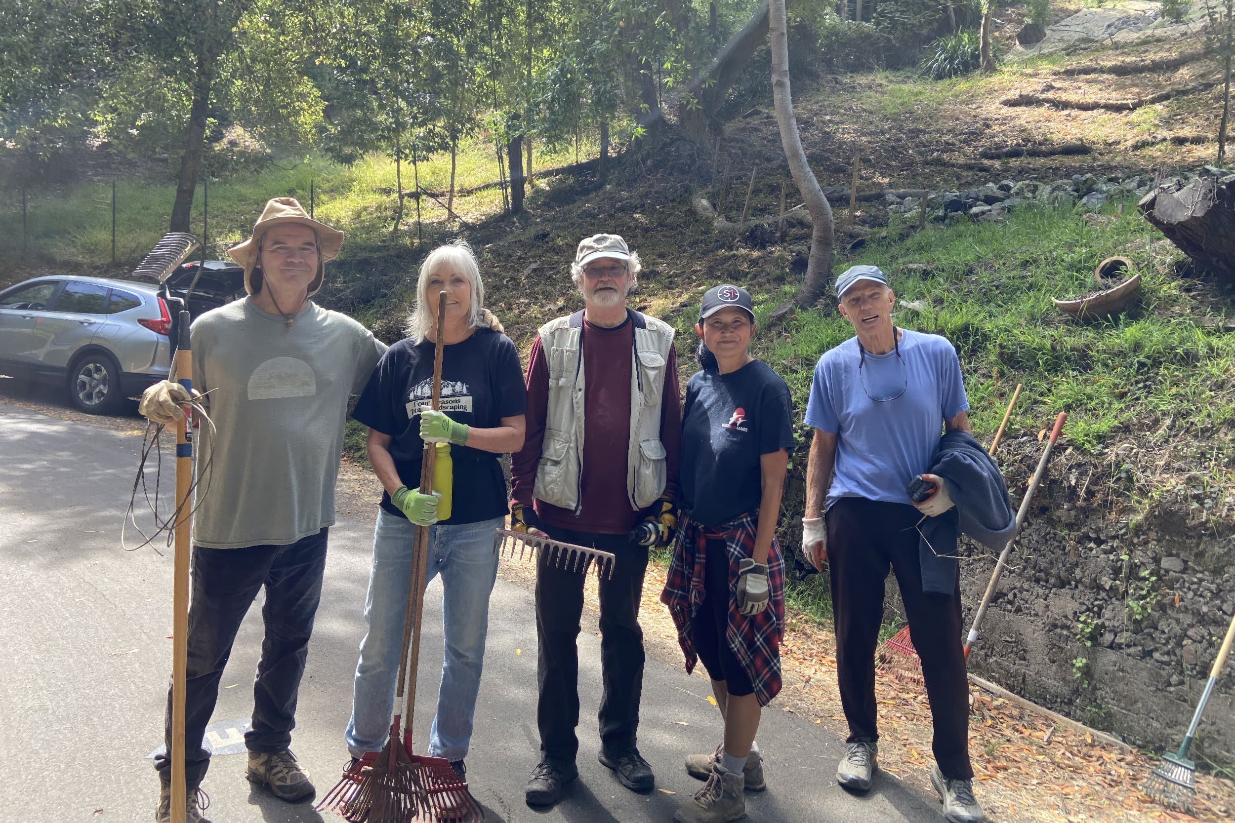 people standing outside smiling for camera with gardening tools