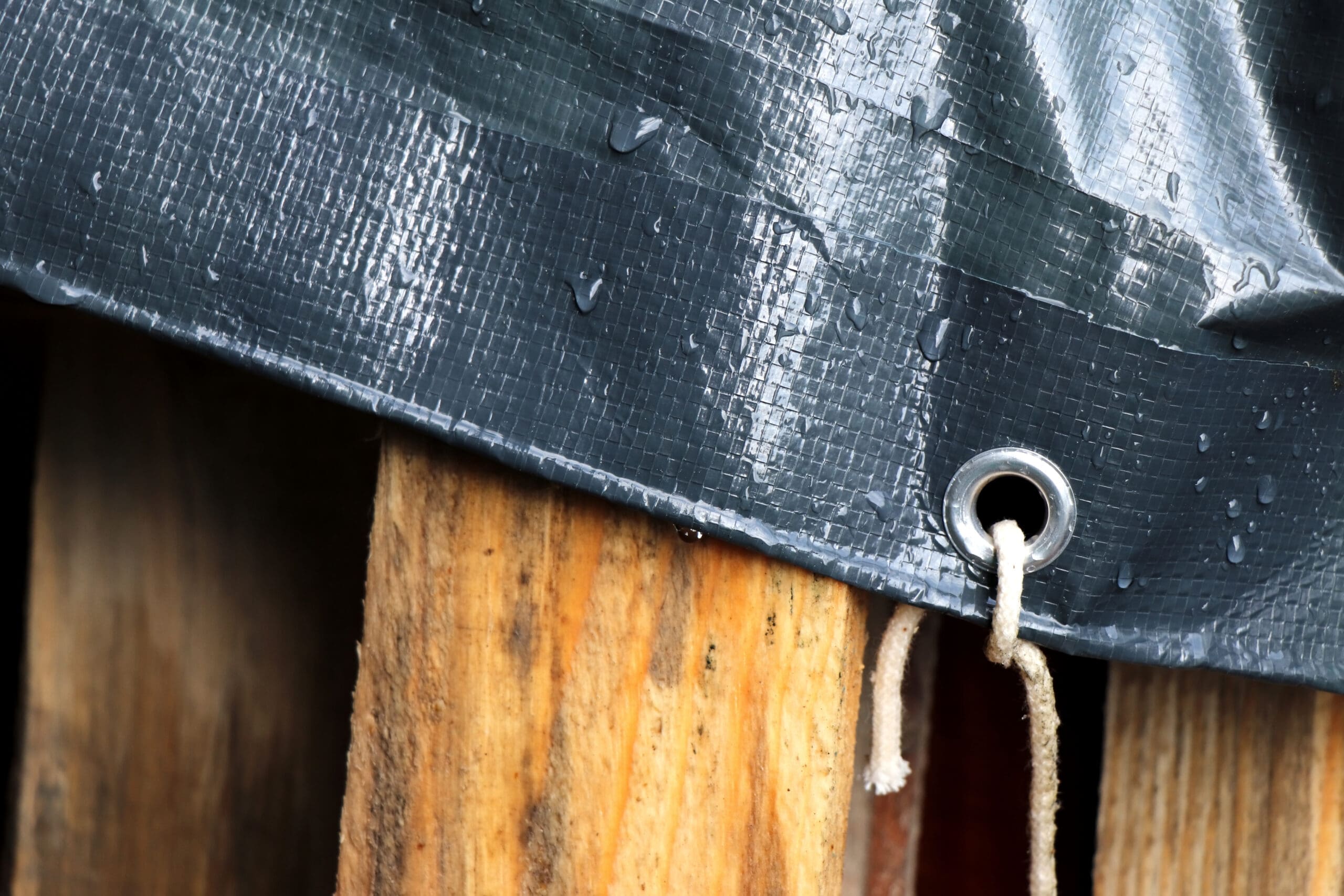 Plastic cloth with water drops. Waterproof surface. Woody palette under grey tarpaulin.
