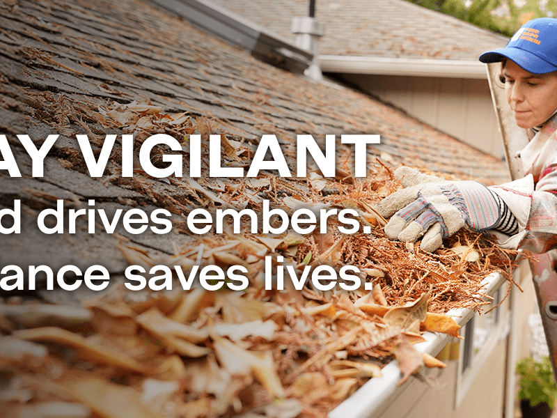 Woman clean leaves from roff gutters. "Stay Vigilant. Wind Drives embers. Vigilance saves lives"